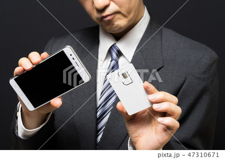 SIMカードとスマホを持って困惑するビジネスマン 47310671