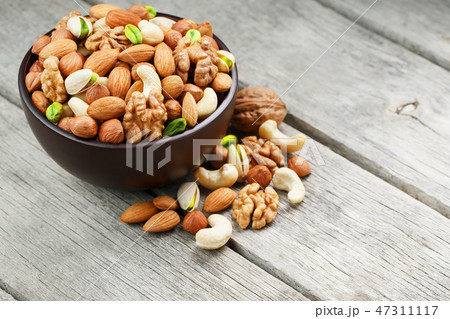 Wooden bowl with mixed nuts on a wooden gray Wooden bowl with mixed nuts on a wooden gray 47311117