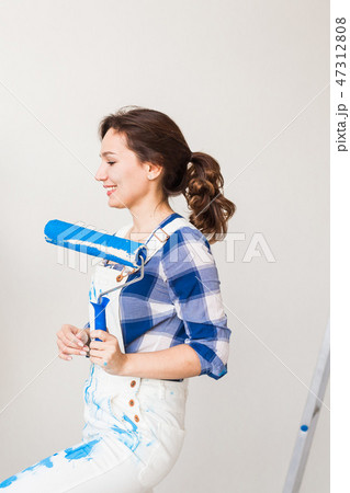 People, redecoration and renovation concept - Beautiful woman paints the wall in new apartment 47312808