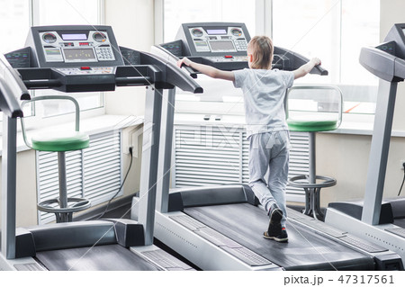 Portrait of a boy on the treadmill in the gym Portrait of a boy on the treadmill in the gym 47317561