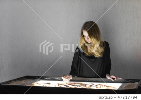 The woman draws on sand, sand animation, sand is pouring from his hands 47317794