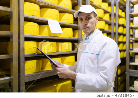 inspector makes notes in the sheet at the cheese warehouse 47318457