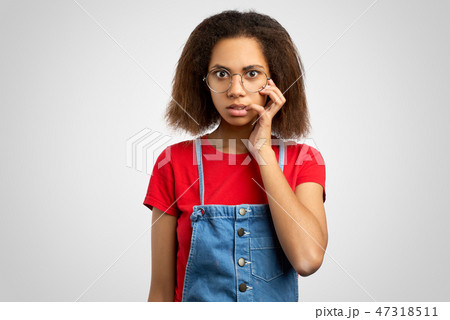 Dark skinned woman keeps fore finger at mouth Dark skinned woman keeps fore finger at mouth 47318511