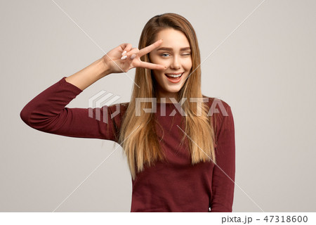 Portrait female showing two fingers and winking Portrait female showing two fingers and winking 47318600