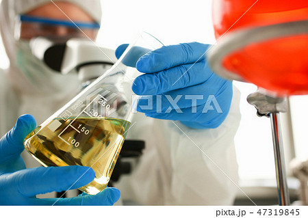 Male chemist look at microscope hold test tube Male chemist look at microscope hold test tube 47319845