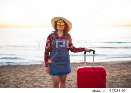 Holiday, travel and tourism concept - Beautiful woman with red suitcase over sandy beach background Holiday, travel and tourism concept - Beautiful woman with red suitcase over sandy beach background 47323464