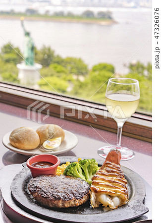 ハンバーグとロブスターテールとチーズ コーン ブロッコリーのランチタイムに眺めれる自由の女神像の窓席の写真素材