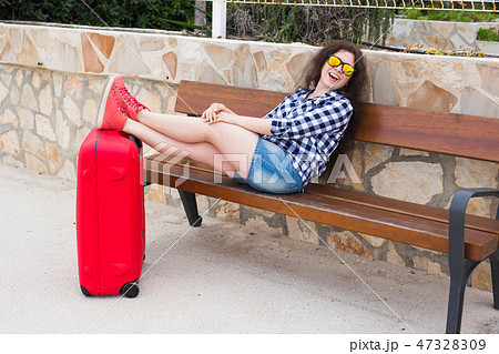 Holiday, travelling and rest concept - young woman resting with feet on suitcase Holiday, travelling and rest concept - young woman resting with feet on suitcase 47328309