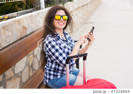 Technology, travelling and people concept - young woman sit on bench in sunny glasses and typing on Technology, travelling and people concept - young woman sit on bench in sunny glasses and typing on 47328909