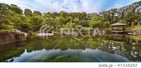 目白庭園の池泉回遊式の鯉が溢れる池の周りに広がる巨大な石、松の木、赤鳥庵と水に反射する六角浮き見堂。 47330202
