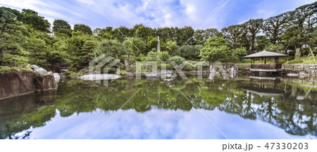 目白庭園の池泉回遊式の鯉が溢れる池の周りに広がる巨大な石、松の木、赤鳥庵と水に反射する六角浮き見堂 47330203