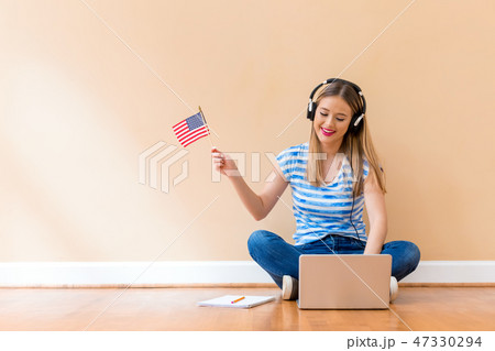 Young woman with USA flag using a laptop computer Young woman with USA flag using a laptop computer 47330294