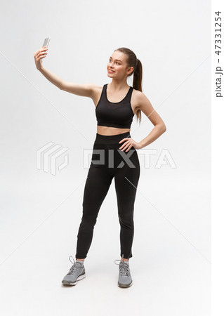 sporty woman making selfie photo on smartphone isolated on a white background. sporty woman making selfie photo on smartphone isolated on a white background. 47331254