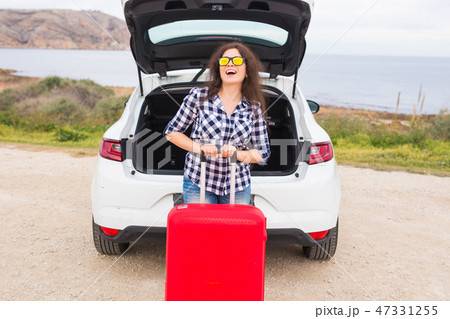 Holiday, travel and tourism concept - young woman with red suitcase on car trip Holiday, travel and tourism concept - young woman with red suitcase on car trip 47331255