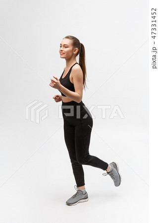 Full length picture of a sports woman running in studio over gray background. 47331452