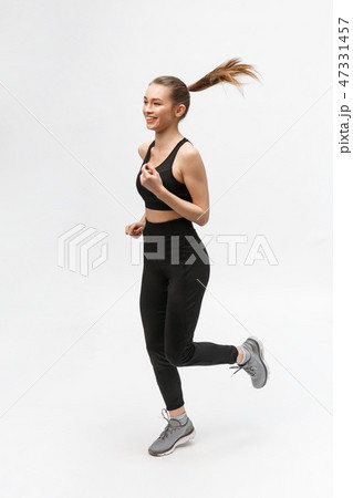 Full length picture of a sports woman running in studio over gray background. Full length picture of a sports woman running in studio over gray background. 47331457