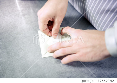 Close up of male hands that hiding paper into envelope Close up of male hands that hiding paper into envelope 47332192
