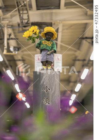 東京の浜松町駅のホームにあるひまわりの花を持ったマネケンピス小便小僧の彫刻。 47332495