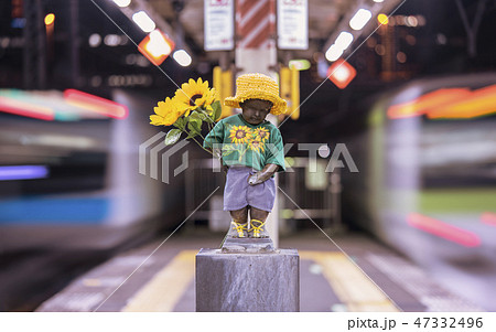 東京の浜松町駅のホームにあるひまわりの花を持ったマネケンピス小便小僧の彫刻。 東京の浜松町駅のホームにあるひまわりの花を持ったマネケンピス小便小僧の彫刻。 47332496