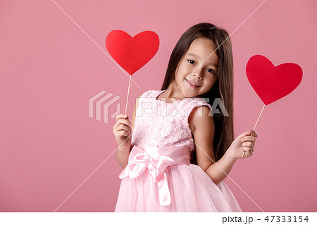 cute little girl in a pink dress holding a paper heart 47333154