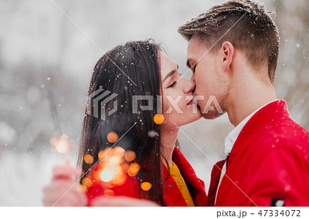 Young man and woman kiss in the winter in the park. Red clothes. In the hands of burning fireworks Young man and woman kiss in the winter in the park. Red clothes. In the hands of burning fireworks 47334072