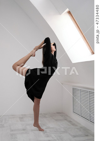 A young female dancer in a black dress is stretching by the window. White Hall, the working class 47334480