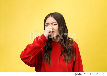 Smell bad. Young lady makes disgusts the smell isolate on yellow background. Smell bad. Young lady makes disgusts the smell isolate on yellow background. 47334503