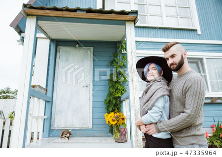 Young woman and man, family, sitting on porch of village house with pumpkins. Young woman and man, family, sitting on porch of village house with pumpkins. 47335964