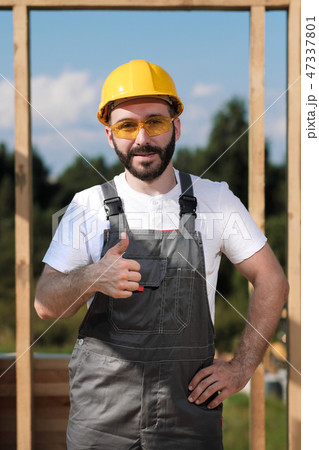 The man is a builder on the roof of a wooden frame house. The man is a builder on the roof of a wooden frame house. 47337801