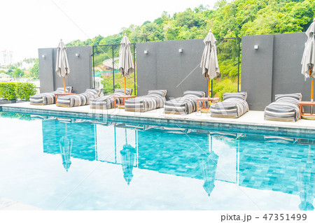 umbrella and chair around outdoor swimming pool 47351499