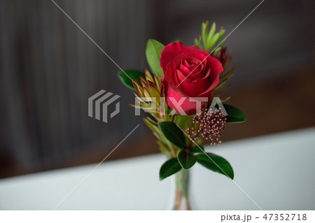 Red rose in a vase on a table with a white tablecloth. 47352718