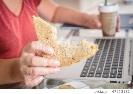 Eating a breakfast sandwich while working 47353182