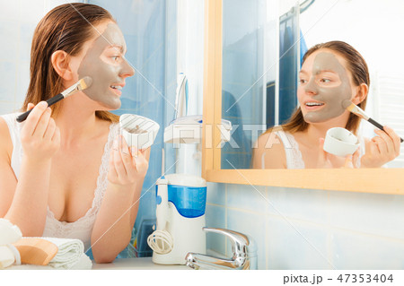 Woman applying mud facial mask Woman applying mud facial mask 47353404