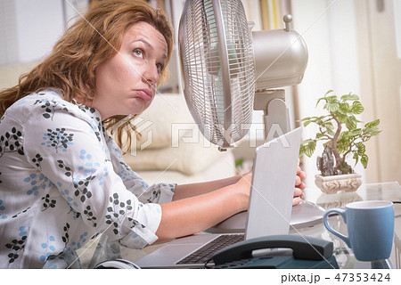 Woman suffers from heat in the office or at home Woman suffers from heat in the office or at home 47353424