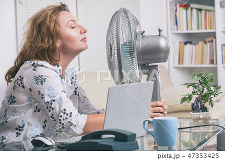 Woman suffers from heat in the office or at home Woman suffers from heat in the office or at home 47353425