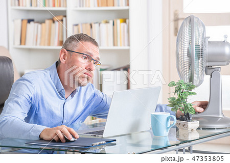 Man suffers from heat in the office or at home Man suffers from heat in the office or at home 47353805