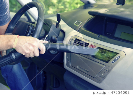 Man hoovering air vent in car 47354002