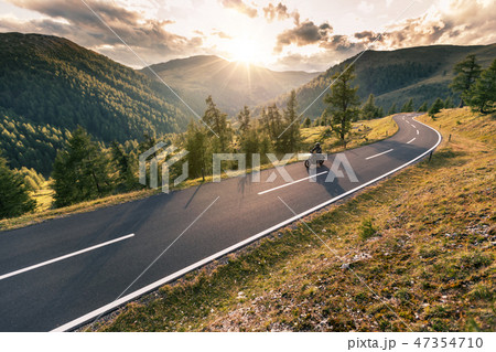 Motorcycle driver riding in Alpine road Motorcycle driver riding in Alpine road 47354710
