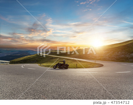 Motorcycle driver riding in Alpine road 47354712