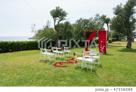 arch and chairs decorated with fresh flowers in red tones for the wedding ceremony on the green lawn arch and chairs decorated with fresh flowers in red tones for the wedding ceremony on the green lawn 47356088