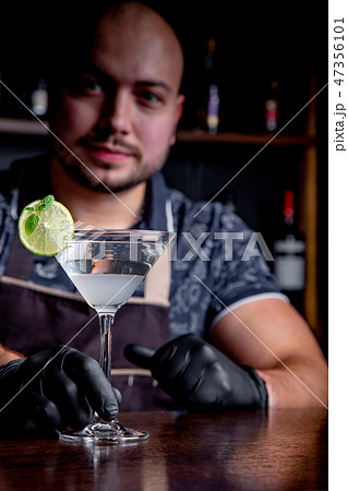 Barman holds out cocktails to client at the bar in restaurant. Welcome Barman holds out cocktails to client at the bar in restaurant. Welcome 47356101
