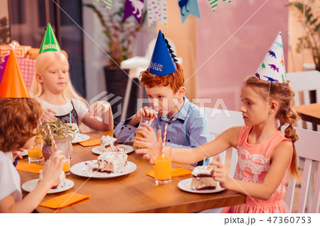 Hungry kids eating cake with great pleasure 47360753
