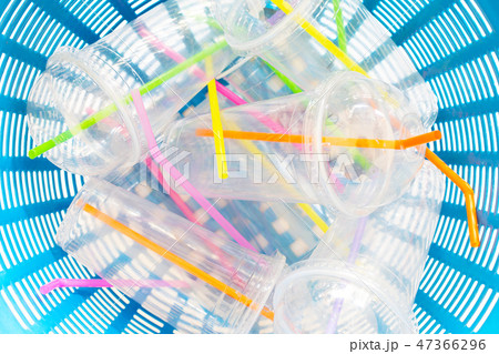 Plastic cups with straws in waste basket. 47366296