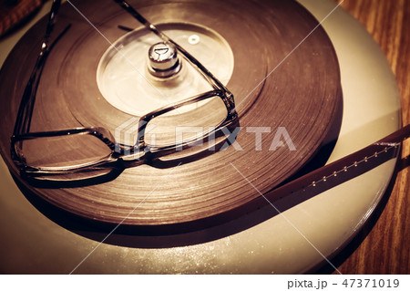Pair of glasses laying on the top of retro film reel. 47371019