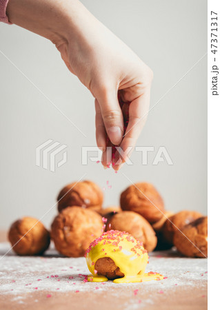 Sprinkling sugar topping on top of a doughnut. Sprinkling sugar topping on top of a doughnut. 47371317