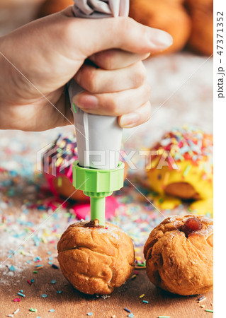 Woman filling homemade doughnut with red jam Woman filling homemade doughnut with red jam 47371352
