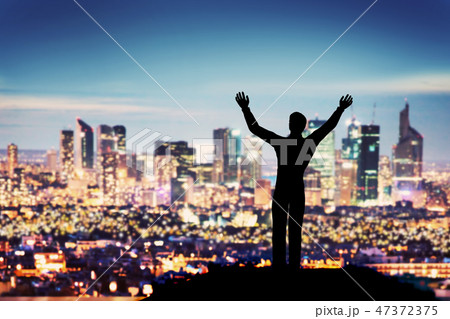 Successful businessman with hands up facing city business downtown Successful businessman with hands up facing city business downtown 47372375