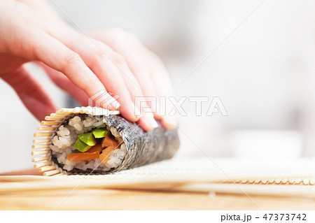 Preparing, rolling sushi. Salmon, avocado, rice and chopsticks on wooden table. 47373742