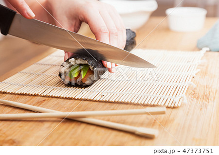 Preparing sushi, cutting. Salmon, avocado, rice and chopsticks on wooden table. 47373751