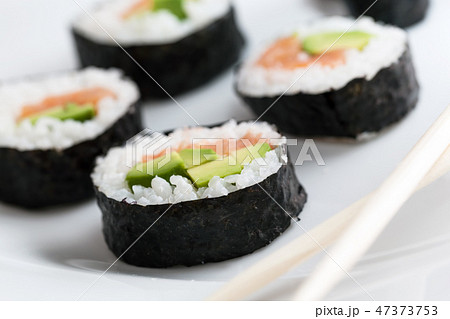 Sushi rolls with salmon, avocado, rice in seaweed and chopsticks on a plate. 47373753